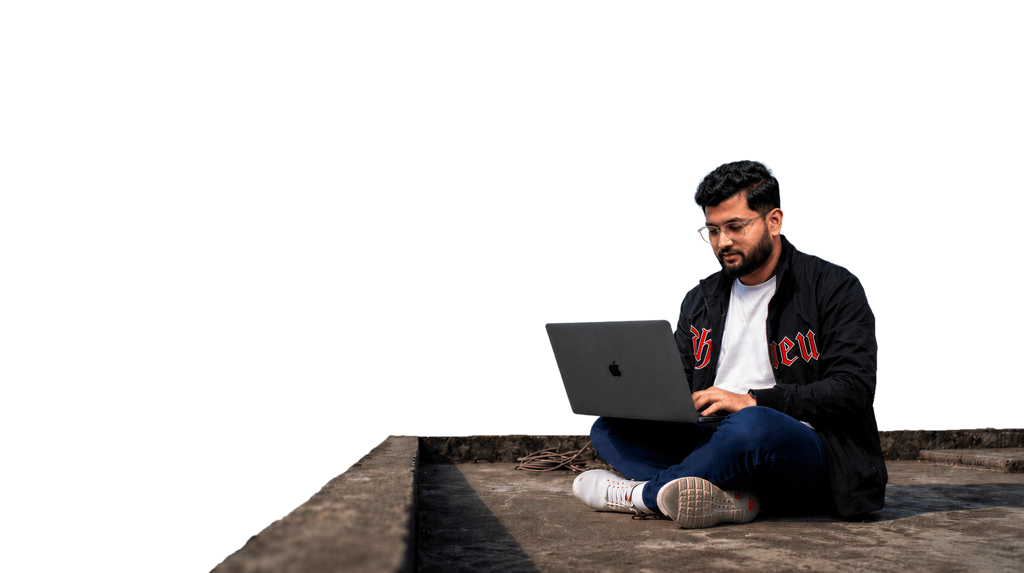 Kamrul working on a laptop, sitting on a rooftop edge against an open sky